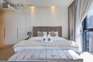 迪拜Mira Holiday Homes - City Walk - Building 5 - Next to Coca Cola Arena的一间卧室配有一张大床和两条白色毛巾