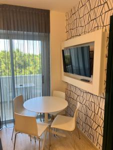 里米尼阿索托丽亚套房酒店的一间带桌椅和电视的用餐室
