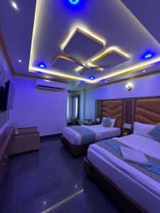 迪马普尔HOTEL COUNTRY INN的酒店客房配有两张床和紫色照明