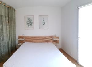 PlourhanLes gîtes aux portes de Saint-Quay-Portrieux的墙上有两张照片的房间的一张白色床