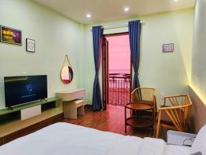 富国Sunset Hotel Phu Quoc - welcome to a mixing world of friends的一间卧室配有一张床、一台电视和一个阳台