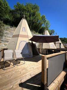 圣塞瓦斯蒂安宜佳拉圣塞巴斯蒂安露营地的帐篷、2把椅子和1张带雨伞的桌子