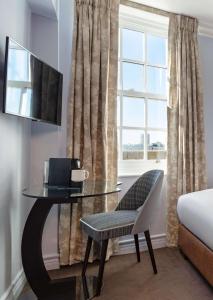 伦敦Radisson Blu Hotel, London Bond Street的客房设有桌子、椅子和窗户。