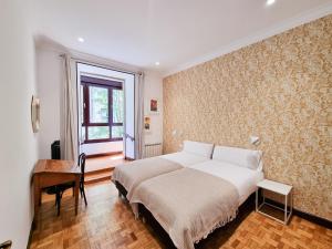 圣塞瓦斯蒂安Costa Getaria - Iberorent Apartments的一间卧室配有一张床、一张书桌和一个窗户。