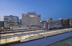 静冈阿索西亚静冈酒店(Hotel Associa Shizuoka)的城市中拥有建筑物的轨道上的火车