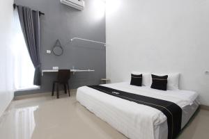 沙拉迪加Capital O 93939 Oikodomeo的卧室配有一张带黑色枕头的大型白色床。