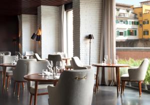 佛罗伦萨佛罗伦萨肖像酒店 -鲁嘉尔诺系列酒店的餐厅设有桌椅和窗户。