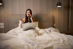 基辅赛纳特麦丹酒店的躺在床上的女人用手机说话