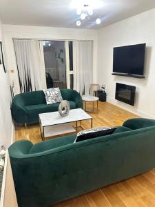 伦敦Cosy 1 Bed Apartment near Excel London的客厅配有2张绿色沙发和1台平面电视