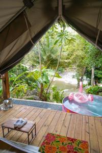 NaguaboEl Yunque Glamping River View at Casa Parcha的木甲板,配有桌子和游泳池