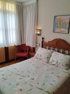 桑提亚纳德玛罗希达罗斯酒店的一间卧室配有一张大床和一张红色椅子