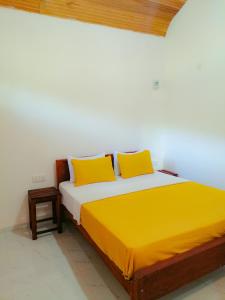 代尼耶耶Serenity Sinharaja的一张带两个黄色枕头的床