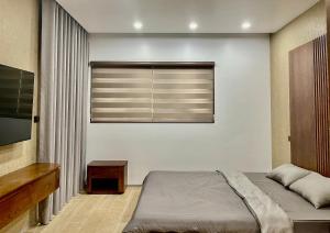 Green Bay Luxury Villa Sonasea Vân Đồn的一间卧室配有一张床和一个带百叶窗的窗户