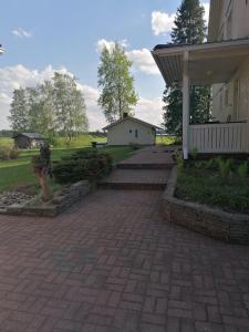 NivalaViihtyisä saunamökki päärakennuksen takana, oma rauha的砖砌的走道,旁边是带门廊的房子