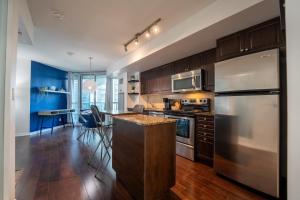 多伦多Fort York Apartments的厨房配有木制橱柜和不锈钢冰箱。