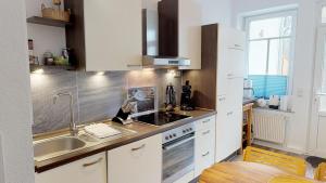 拉博埃Haus Friedrichstr. 16的厨房配有白色橱柜、水槽和桌子