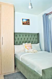 内罗毕Magazi suites 3的小卧室配有一张带绿色床头板的床