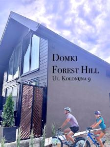 米兹多洛杰Forest Hill domki - Międzyzdroje -KLIMATYZACJA的两人在房子前骑车