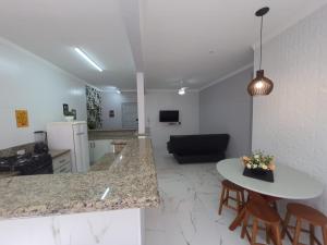 大普拉亚BEIRA MAR I - TUPI - 15 metros da praia - 2 dormitórios com VARANDA - WI FI e acomoda até 8 pessoas - ESTACIONAMENTO Gratuito的厨房以及带桌椅的起居室。