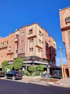 瓦尔扎扎特IAZAL Hotel Ouarzazate的一座高大的建筑,前面有汽车停放