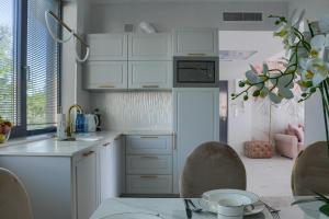 尤斯托尼莫斯基Apartament Nadmorski Luksus - Boulevard的厨房配有白色橱柜和桌椅