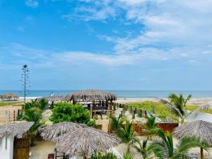 普拉亚斯Un Dia Boutique Resort的一片带一些草伞和海洋的海滩