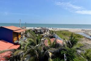 普拉亚斯Un Dia Boutique Resort的棕榈树和大海海滩上的度假屋