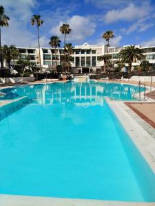 科斯塔特吉塞Bungalow GOA Pool view, Playa Roca residence sea front access - Free AC - Wifi的一个大型蓝色游泳池,酒店背景