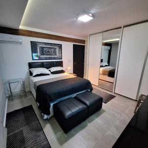 桑托斯Oceanview Santos canal 2的一间卧室设有一张大床和一个黑色皮革座椅。