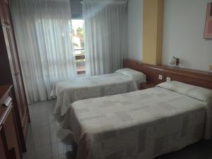 索拉雷斯Pensión Rada的酒店客房设有两张床和窗户。