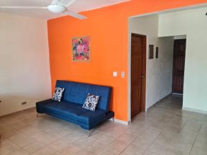 普拉亚埃尔莫萨Hermosa Paradise的橙色墙壁的房间里一张蓝色的沙发
