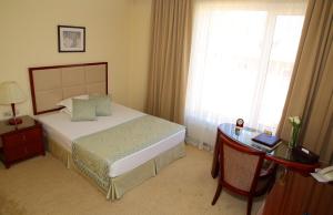 比什凯克比什凯克公园酒店的一间卧室配有一张床、一张书桌和一个窗户。