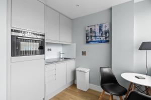 切姆Luxurious One Bedroom Apartment in Bond Street的厨房配有白色橱柜和桌椅
