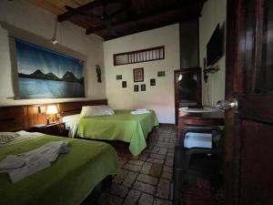 IníridaToninas Hotel的酒店客房设有两张床,墙上挂有绘画作品