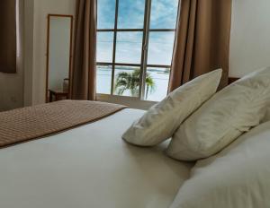 弗洛勒斯阿米莉亚卡萨酒店的一张带枕头的床和一扇带棕榈树的窗户
