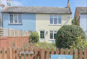 AldringhamKnodishall - Newly renovated 2 bed holiday home, near Aldeburgh, Leiston and Thorpeness的木制围栏后面的蓝色和白色房子