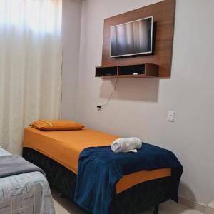 帕尔马斯Flat ideal para familia e grupos de amigos proximo ao aeroporto e rodoviária的卧室配有一张床,墙上配有电视。