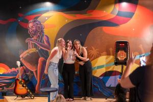 怀卢库Howzit Hostels的三个女人站在壁画前面的舞台上
