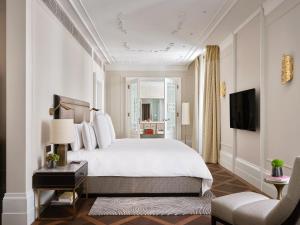 维也纳Rosewood Vienna的卧室配有一张白色大床和一把椅子