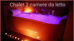 奥斯塔Atmosfera e vista mozzafiato Chalets的配有紫色灯的浴缸; 粉笔相机回声