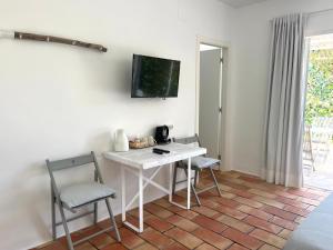 哈维亚Habitación con jardín y terraza en el Tosalet的一间设有一张桌子和两把椅子的房间,墙上设有一台电视机