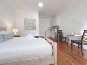 悉尼307 Malabar Road Rental Units In Sydney的一间带白色床的卧室和一间厨房