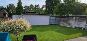 文迪施里茨ferienhaus-am-scharmützelsee的后院设有白色的围栏和绿色的草坪