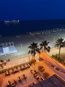 ErdemliAngel Beach Hotel Kızkalesi Mersin的享有海滩的夜间美景,配有椅子和棕榈树