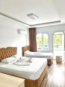 ErdemliAngel Beach Hotel Kızkalesi Mersin的带2扇窗户的客房内的2张床