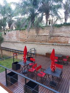 贝伦埃斯科巴La Morada Rentals Apartments的一个带桌子和红色椅子的甲板和墙壁