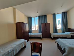 阿布扎比Oasis Hostel的客房设有三张床、椅子和窗户。