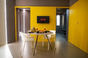 特拉帕尼Fiveplace Design Suites & Apartments的用餐室设有黄色的墙壁和桌椅