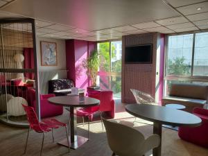埃皮纳勒Mercure Epinal Centre的餐厅设有2张桌子和椅子,墙壁粉红色