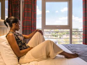 内罗毕内罗毕西兰宜必思风格酒店的坐在床上看着窗外的女人